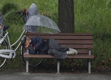 pensionato che dorme su una panchina